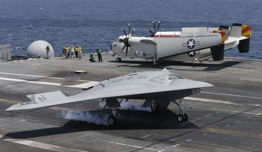 A X47-B Navy drone touches down as it lands aboard the nuclear aircraft carrier USS George H. W. Bush off the Coast of Virginia Wednesday, July 10, 2013. It is the first landing by a drone on a Navy carrier. (AP Photo/Steve Helber)
