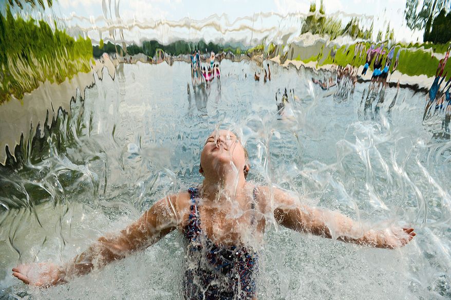 Olivia, 8, of Olathe, Kan., cools off in a waterfall at the Washington Navy Yard on Monday. Temperatures in the high 90s are expected to linger through Friday. (Andrew Harnik/The Washington Times)