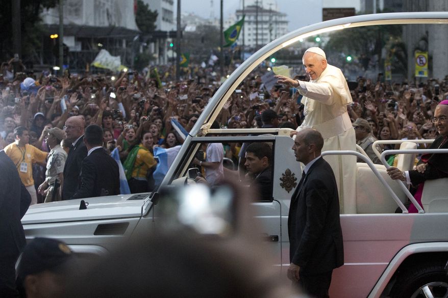 Pope Francis waves from his popemobile as he makes his way into central Rio de Janeiro, Brazil, Monday, July 22, 2013. The pontiff arrived for a seven-day visit in Brazil, the world's most populous Roman Catholic nation. During his visit, Francis will meet with legions of young Roman Catholics converging on Rio for the church's World Youth Day festival. (AP Photo/Felipe Dana)