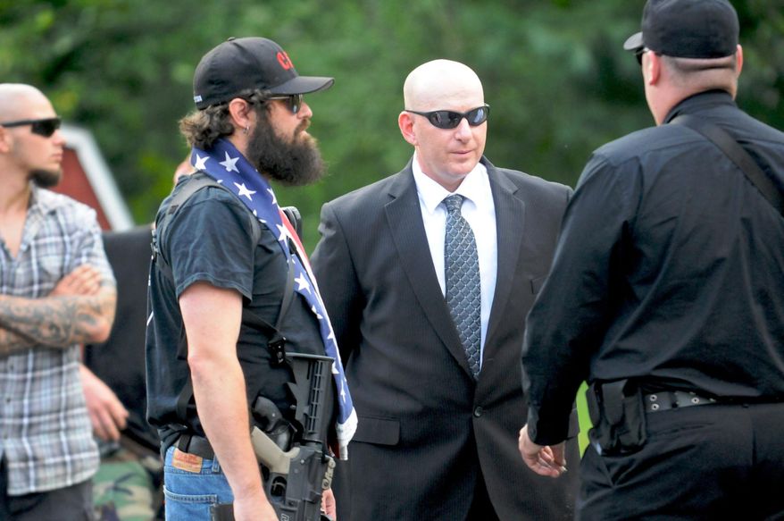 Gilberton Police Chief Mark Kessler, center, talks with members of the Constitutional Security Force outside Gilberton Borough Hall before the Gilberton Borough Council meeting in Mahanoy Plane, Pa., Wednesday, July 31, 2013. The Gilberton Borough Council voted to suspend borough police Chief Mark Kessler for 30 days without pay at Wednesday night's borough council meeting. (AP Photo/The Republican-Herald, Jacqueline Dormer)