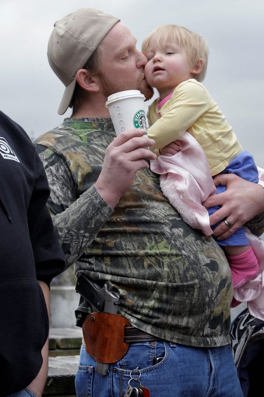 Greg Dement takes daughter Elicia to watch a gun control rally in Seattle. He shows support for Starbucks, which quietly allows gun owners to carry visible weapons. (Associated Press)