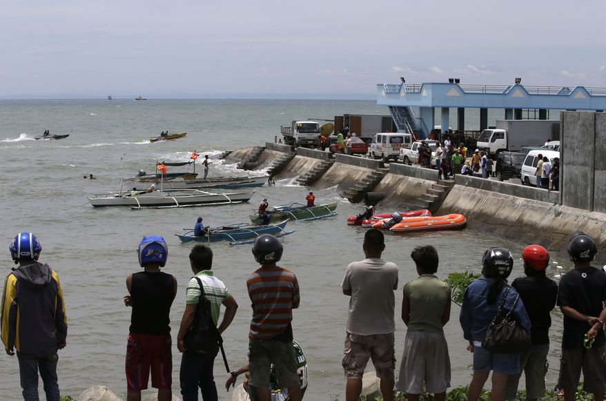 A crowd watches as divers continue their search and rescue operation off Talisay coast, Cebu province on Aug. 18, 2013 following a collision of the passenger ferry MV Thomas Aquinas and the cargo ship MV Sulpicio Express Siete in central Philippines on Aug. 16. Divers plucked two more bodies from the sunken passenger ferry on Sunday and scrambled to plug an oil leak in the wreckage after a collision with a cargo ship. The accident near the central Philippine port of Cebu that has left 34 dead and more than 80 others missing. (Associated Press)