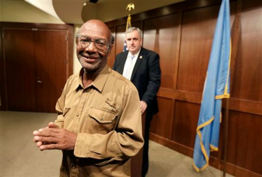 Glen James, of Boston, left, smiles in the direction of members of the media as Boston Police Commissioner Edward Davis, right, looks on during a news conference at the police headquarters, in Boston on Monday, Sept. 16, 2013. James, who is homeless, turned in a backpack containing $2,400 in U.S. currency, almost $40,000 in traveler's checks, as well as Chinese passports and other personal papers to police after finding the items in a Boston mall on Sept. 14, 2013. (AP Photo/Steven Senne)