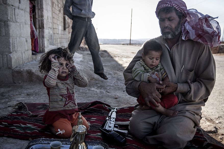 A Free Syrian Army fighter holds his son outside their home in Habit village, the Syrian central province of Hama, Wednesday, Sep. 25, 2013. (AP Photo)