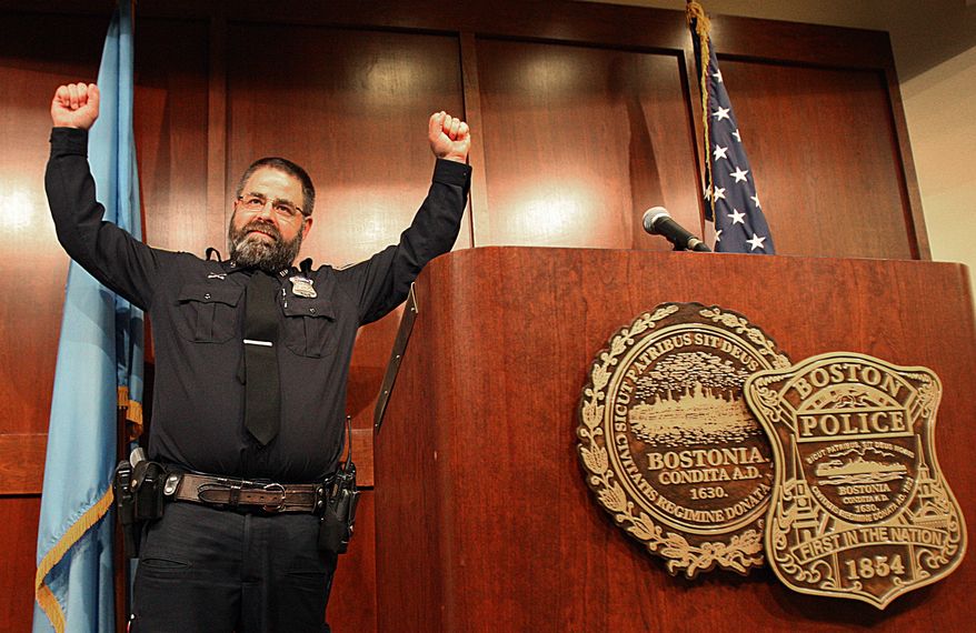 Boston Police Officer Steve Horgan, raises his hands as he poses for a photograph during a news conference on Tuesday, Oct. 15, 2013 in Boston. Horgan says he's humbled by the attention he's received since photographs of him raising his arms in jubilation after the Boston Red Sox hit a grand slam against the Detroit Tigers appeared in newspapers and on the Internet. The photos show Horgan's arms raised in the same frame as the upturned legs of Tigers outfielder Torii Hunter as he tumbles into the Fenway Park bullpen, where Horgan was working a security detail. David Ortiz's grand slam tied Sunday's game 5-5, and the Red Sox went on to a 6-5 victory. (AP Photo/The Boston Globe, Suzanne Kreiter) BOSTON HERALD OUT, QUINCY OUT; NO SALES