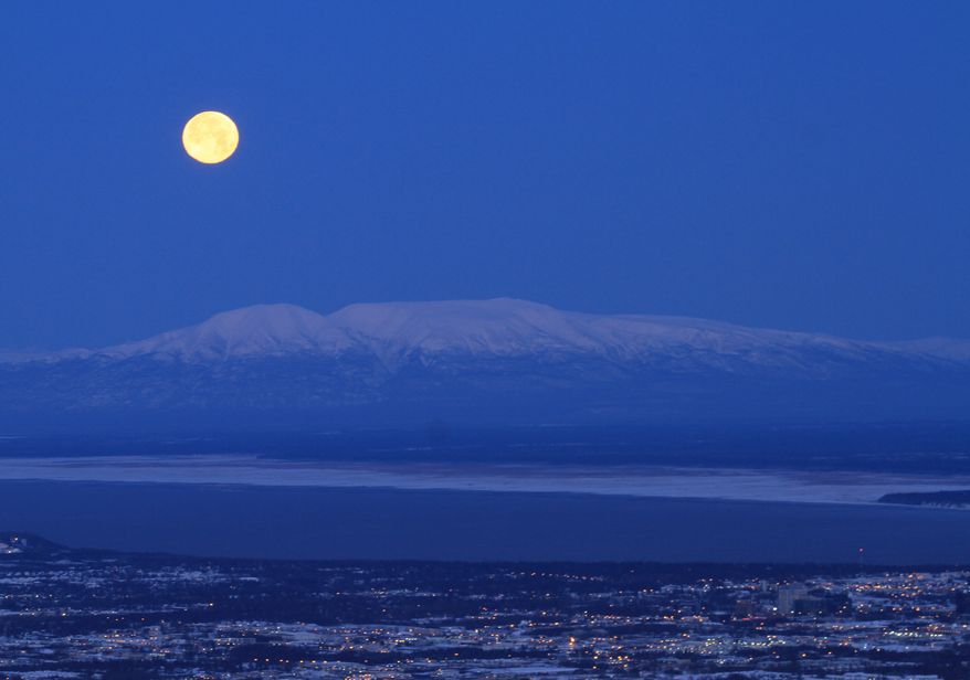 A full moon sets over Mount Susitna in Anchorage, Alaska, Nov. 17, 2013. (AP Photo/Dan Joling)