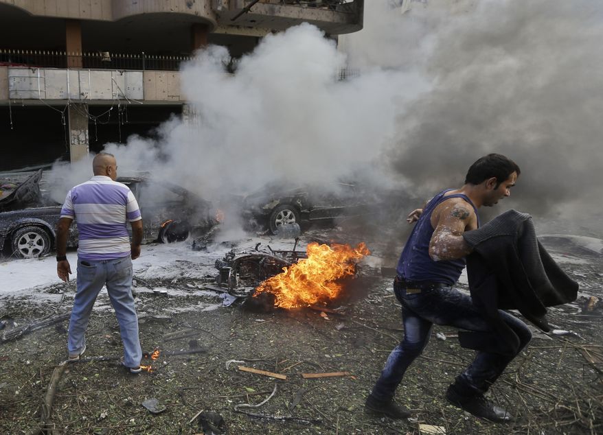 A Lebanese man runs in front of a burned car, at the scene where two explosions have struck near the Iranian Embassy killing many, in Beirut, Lebanon, Tuesday Nov. 19, 2013. The blasts in south Beirut's neighborhood of Janah also caused extensive damage on the nearby buildings and the Iranian mission. The area is a stronghold of the militant Hezbollah group, which is a main ally of Syrian President Bashar Assad in the civil war next door. It's not clear if the blasts are related to Syria's civil war. (AP Photo/Hussein Malla)