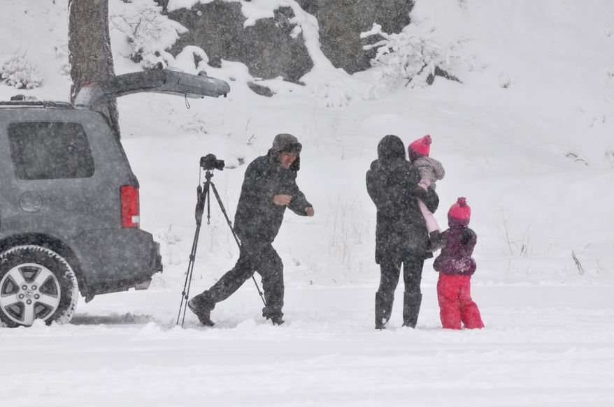 Chris Calma (left) of Rancho Cucamonga, Calif., runs to take a picture with his family in the snow after setting up his camera on self-timer mode in Wrightwood, Calif., on Friday, Nov 22, 2013. (AP Photo/The Victor Valley Daily Press, David Pardo)