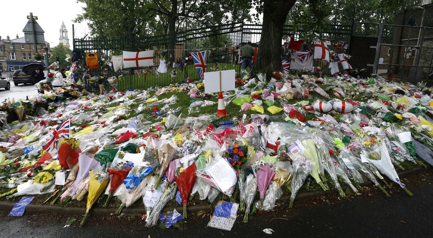 ** FILE ** This Tuesday, May 28, 2013, file photo shows floral tributes at the scene where 25-year-old soldier of the Royal Regiment of Fusiliers Lee Rigby was attacked and killed, near Woolwich Barracks in London. (AP Photo/Kirsty Wigglesworth)