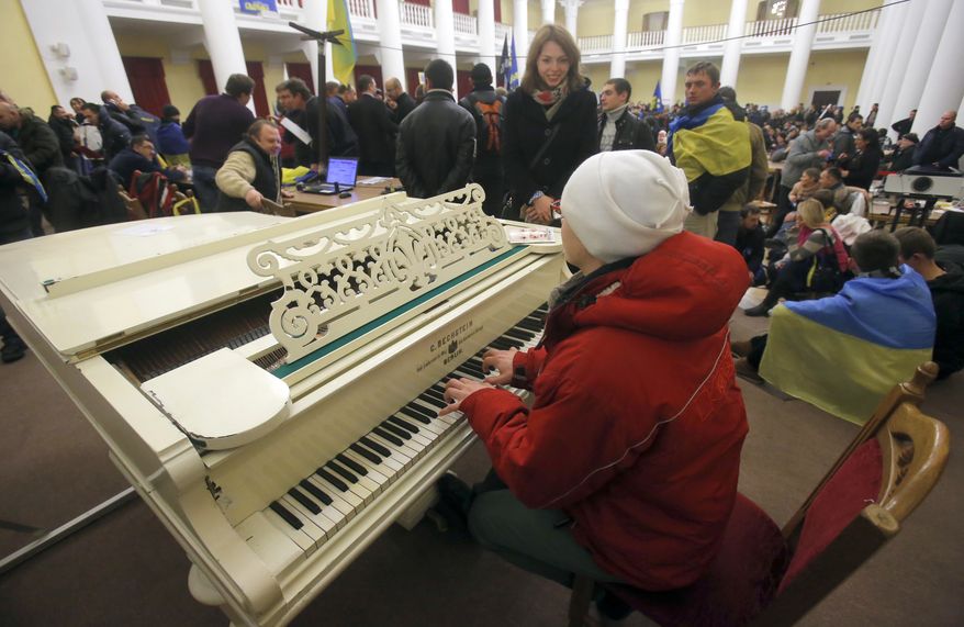 A protester plays the piano in the Kiev city council building which they occupied in downtown Kiev, Ukraine, on Sunday, Dec. 1, 2013. A protest by about 300,000 Ukrainians angered by their government's decision to freeze integration with the West turned violent Sunday, when a group of demonstrators besieged the president's office and police drove them back with truncheons, tear gas and flash grenades. Dozens of people were injured. (AP Photo/Sergei Grits)