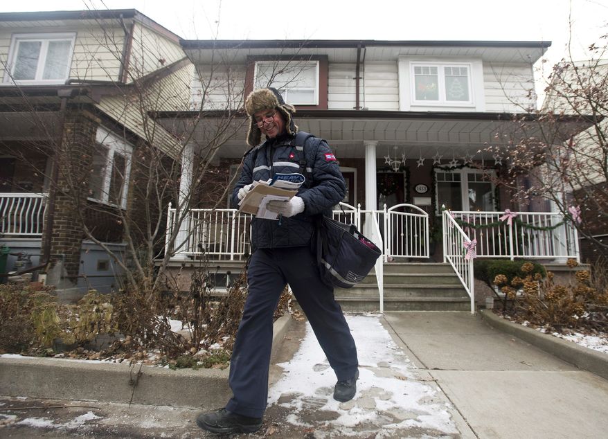 A Canada Post employee delivers mail and parcels to residential homes in Toronto on Wednesday, Dec. 11, 2013. The nation's postal service said it will phase out home delivery within urban centers within the next five years as it begins to post significant financial losses because of growing use of digital communication. Canada Post, a government corporation, said it will replace foot delivery with community mail boxes, (AP Photo/The Canadian Press, Nathan Denette)