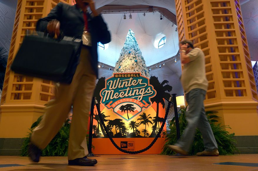 Guests walk past a sign welcoming attendees of baseball's winter meetings in Lake Buena Vista, Fla., Wednesday, Dec. 11, 2013.(AP Photo/Phelan M. Ebenhack)