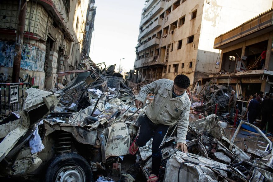 An Egyptian man makes his way through rubble at the scene of an explosion at a police headquarters building that killed at least a dozen people, wounded more than 100, and left scores buried under the rubble, in the Nile Delta city of Mansoura, 110 kilometers (70 miles) north of Cairo, Egypt, Tuesday, Dec. 24, 2013. The country's interim government accused the Muslim Brotherhood of orchestrating the attack, branding it a "terrorist organization." No one immediately claimed responsibility for the bombing, which came a day after an al-Qaida-inspired group called on police and army personnel to desert or face death at the hands of its fighters. (AP Photo/Ahmed Ashraf)