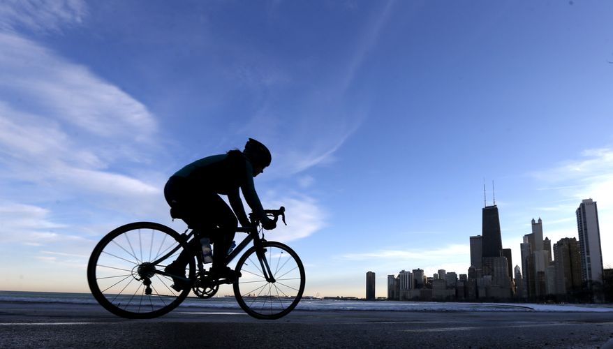 In this photo taken Wednesday, Dec. 18, 2013, in Chicago, a lone cyclists navigates the bike path along Lake Michigan at the North Ave. beach. An early bone-zapping blast of snow and ice hasn’t stopped a surprising number of cyclists from spinning through the slush in Chicago this winter, thanks in part to a city so serious about accommodating them that it deploys mini-snow plows to clear bike lanes. A city councilwoman's recent proposal to institute a $25 annual cycling tax set off a lively debate. Mayor Rahm Emanuel has made bike lanes and bike programs a signature issue, believing it makes downtown an attractive place for bright young people and innovative companies. (AP Photo/Charles Rex Arbogast)
