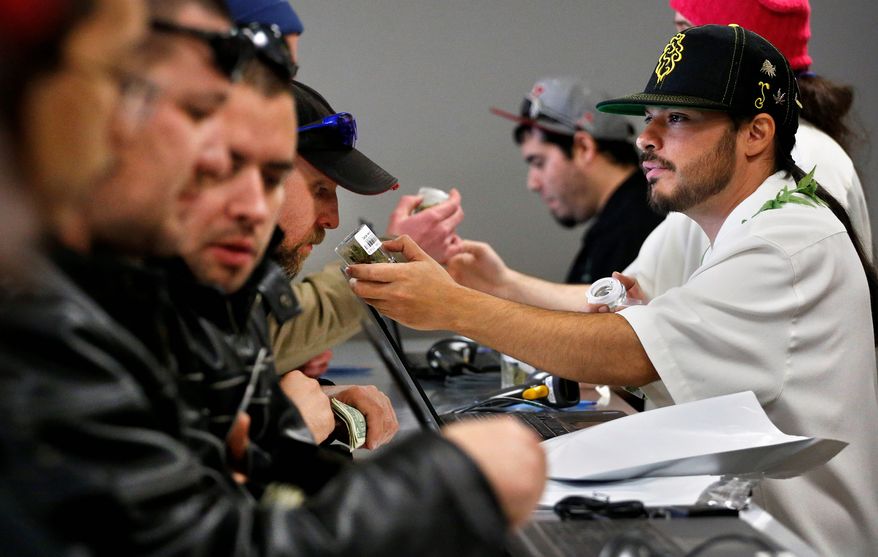 GREEN WEDNESDAY: David Marlow, an employee at the Medicine Man store in Denver, gives a customer at the crowded counter a whiff of a strain of marijuana Wednesday as Colorado began legal retail sales of pot for recreational use. (Associated Press)