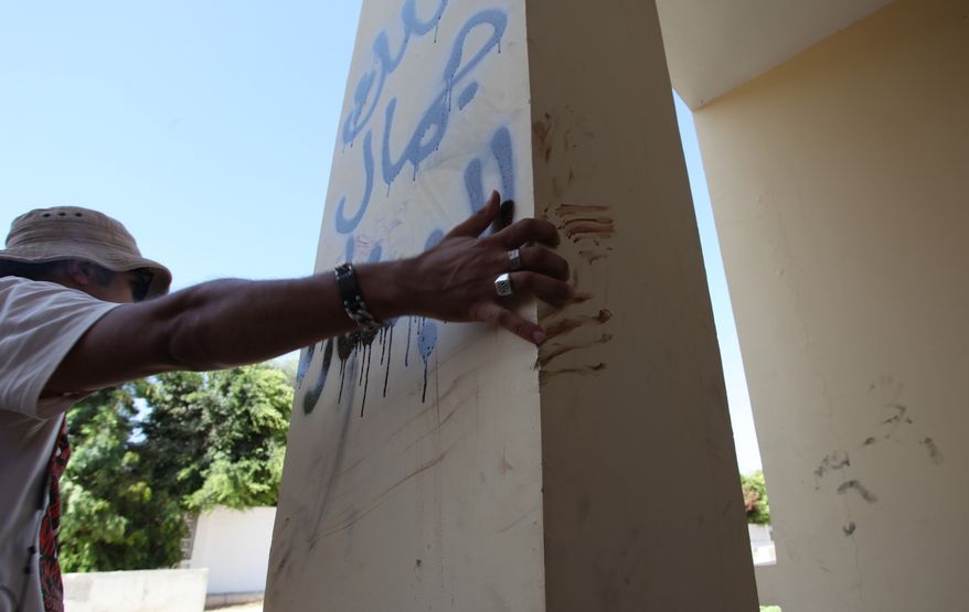 A Libyan man explains that the bloodstains on the column are from one the American staff members who grabbed the edge of the column while he was evacuated, after an attack that killed four Americans, including Ambassador Chris Stevens on the night of Tuesday, Sept. 11, 2012, in Benghazi, Libya, Thursday, Sept. 13, 2012. The American ambassador to Libya and three other Americans were killed when a mob of protesters and gunmen overwhelmed the U.S. Consulate in Benghazi, setting fire to it in outrage over a film that ridicules Islam's Prophet Muhammad. Ambassador Chris Stevens, 52, died as he and a group of embassy employees went to the consulate to try to evacuate staff as a crowd of hundreds attacked the consulate Tuesday evening, many of them firing machine-guns and rocket-propelled grenades. Arabic writing reads, " Villa of Jamal al Beshary". which was written by the owner to protect the property from another attack. (AP Photo/Mohammad Hannon)
