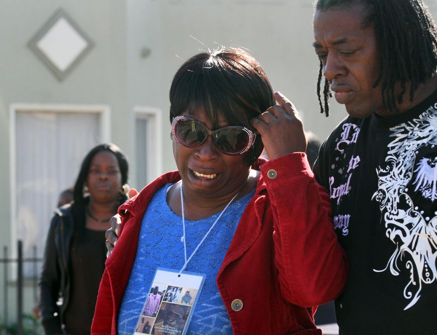 In this photo from Jan. 20, 2014, Dinyal New, center, mother of Lamar Broussard, who was killed Sunday with his best friend Derryck Harris, both 19, mourns the loss of the second son to have been killed this year, at the scene of the killing on Longfellow Avenue in Oakland, Calif. Lee Weathersby III, 13, New's other son, died on Jan. 1 after having been shot as he walked home from a New Year's Eve party. (AP Photo/The Oakland Tribune, Laura A. Oda)
