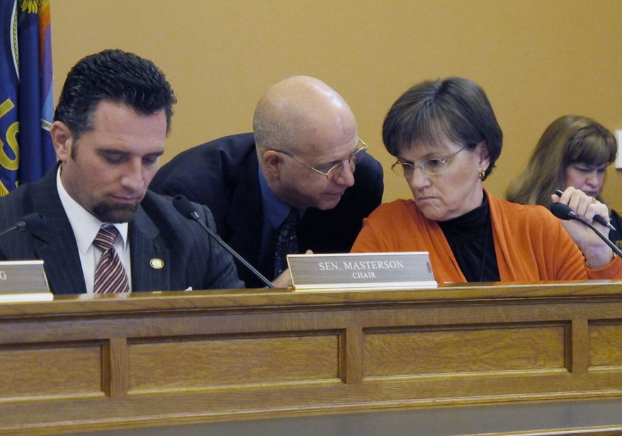 Kansas state Sen. Laura Kelly, right, a Topeka Democrat, confers with J.G. Scott, center, the top budget analyst on the Legislature's research staff, during a Senate Ways and Means Committee hearing on the prison system's budget, Tuesday, Jan. 21, 2014, at the Statehouse in Topeka, Kan. To the left, committee Chairman Ty Masterson, an Andover Republican, follows testimony. (AP Photo/John Hanna)