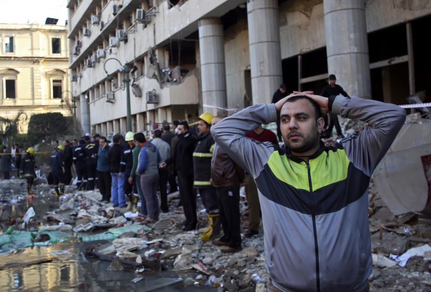 An Egyptian man stands in rubble after an explosion at the Egyptian police headquarters in downtown Cairo, Friday, Jan. 24, 2014. Three bombings hit high-profile areas around Cairo on Friday, including a suicide car bomber who struck the city's police headquarters, killing several people in the first major attack on the Egyptian capital as insurgents step up a campaign of violence following the ouster of the Islamist president. (AP Photo/Khalil Hamra)