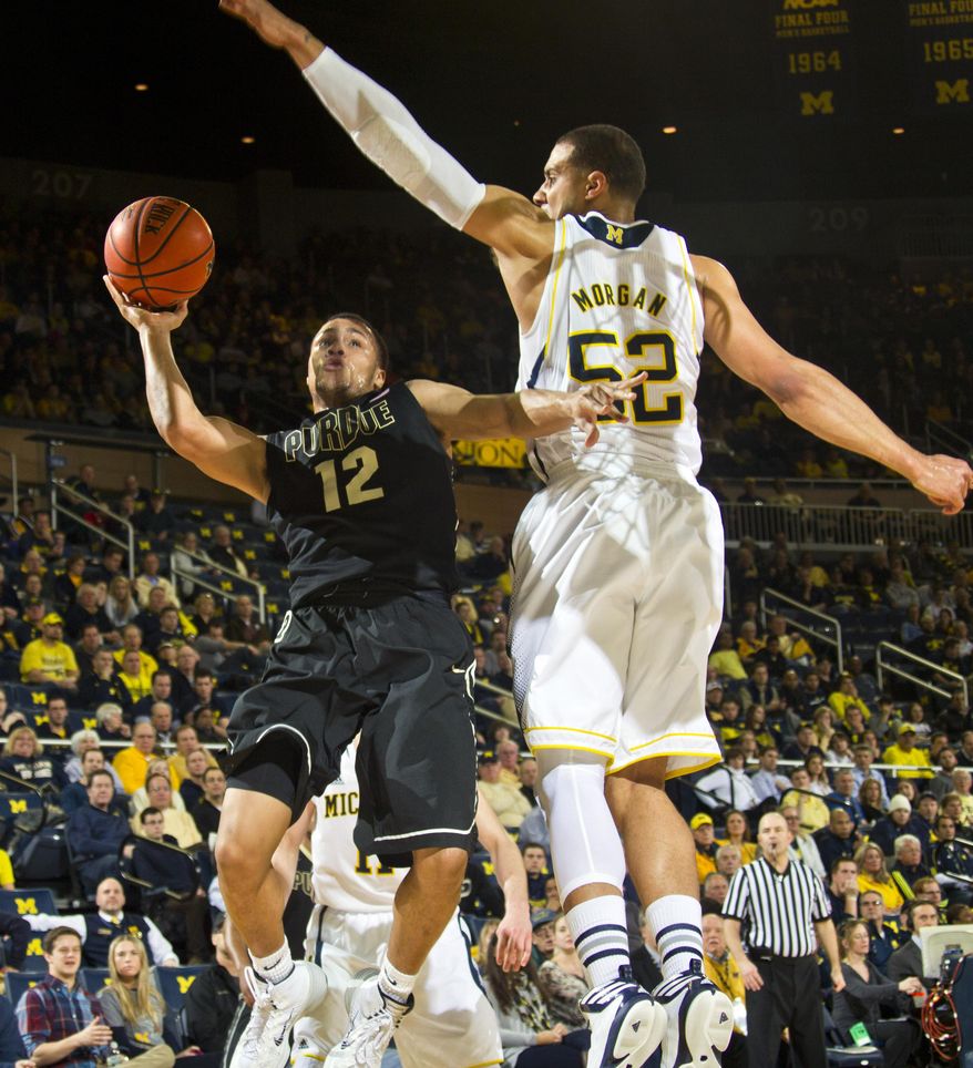 Purdue guard Bryson Scott (12) tries to make a basket while defended by Michigan forward Jordan Morgan (52) in the second half of an NCAA college basketball game in Ann Arbor, Mich., Thursday, Jan. 30, 2014. Michigan won 75-66. (AP Photo/Tony Ding)