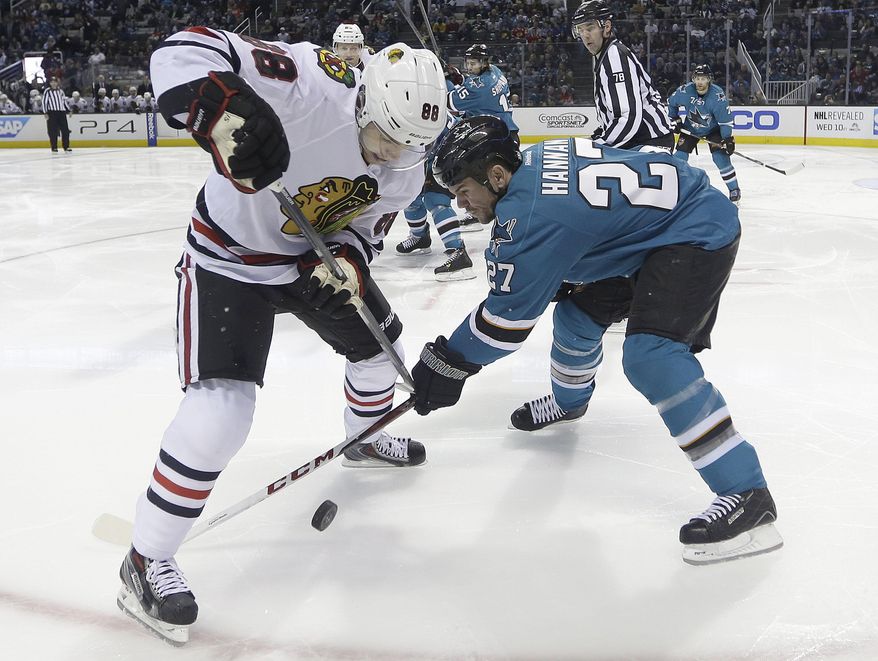 Chicago Blackhawks right wing Patrick Kane (88) tangle up for the puck against San Jose Sharks defenseman Scott Hannan (27) during the second period of an NHL hockey game in San Jose, Calif., Saturday, Feb. 1, 2014. (AP Photo/Tony Avelar)