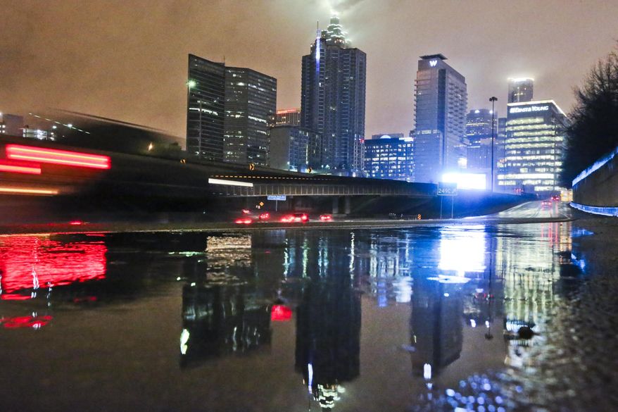 Motorists, reflected in a puddle, move on the downtown connector Tuesday, Feb. 11, 2014 without hindrance from ice in Atlanta. . In a dire warning Tuesday, forecasters said a "catastrophic" winter storm threatened to bring a thick layer of ice to Georgia and other parts of the South, causing widespread power outages that could leave people in the dark for days. (AP Photo/Atlanta Journal-Constitution, John Spink) MARIETTA DAILY OUT; GWINNETT DAILY POST OUT; LOCAL TV OUT; WXIA-TV OUT; WGCL-TV OUT