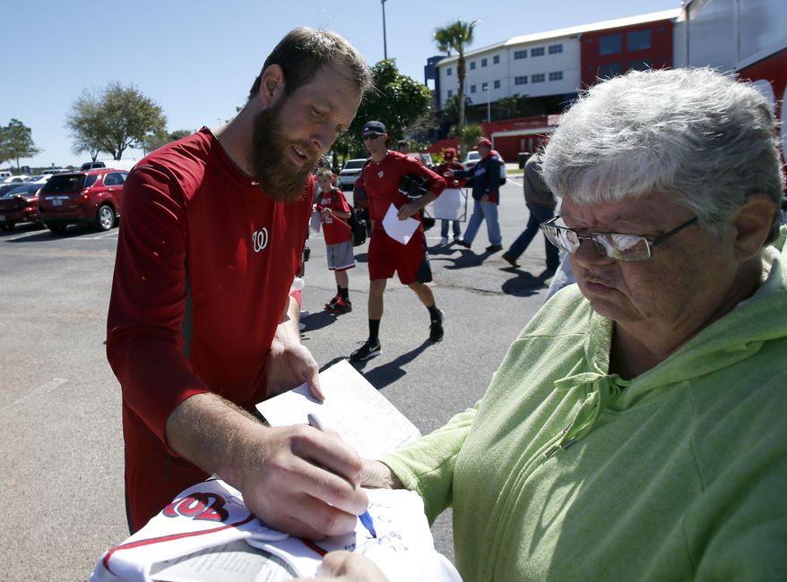Washington Nationals relief pitcher Ryan Mattheus signs an autograph for a fan during a break in their spring training baseball workout, Friday, Feb. 14, 2014, in Viera, Fla. (AP Photo/Alex Brandon)