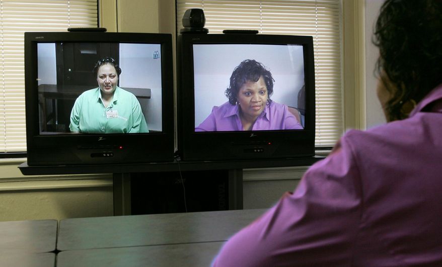 FILE - In this Tuesday, Dec. 7, 2004 photo, prison inmate Vanessa Buffington, left, talks in Marysville, Ohio with her former sister-in-law, Barbara Palmore, right, in Cleveland via a video link from the office of The Eastside Consortium Prison Visitation Program/Project IMPACT. Jail officials in two other Ohio counties, Montgomery and Warren, are planning to allow inmates to meet with their lawyers, family and friends using remote video access. (AP Photo/The Plain Dealer, David I. Andersen)