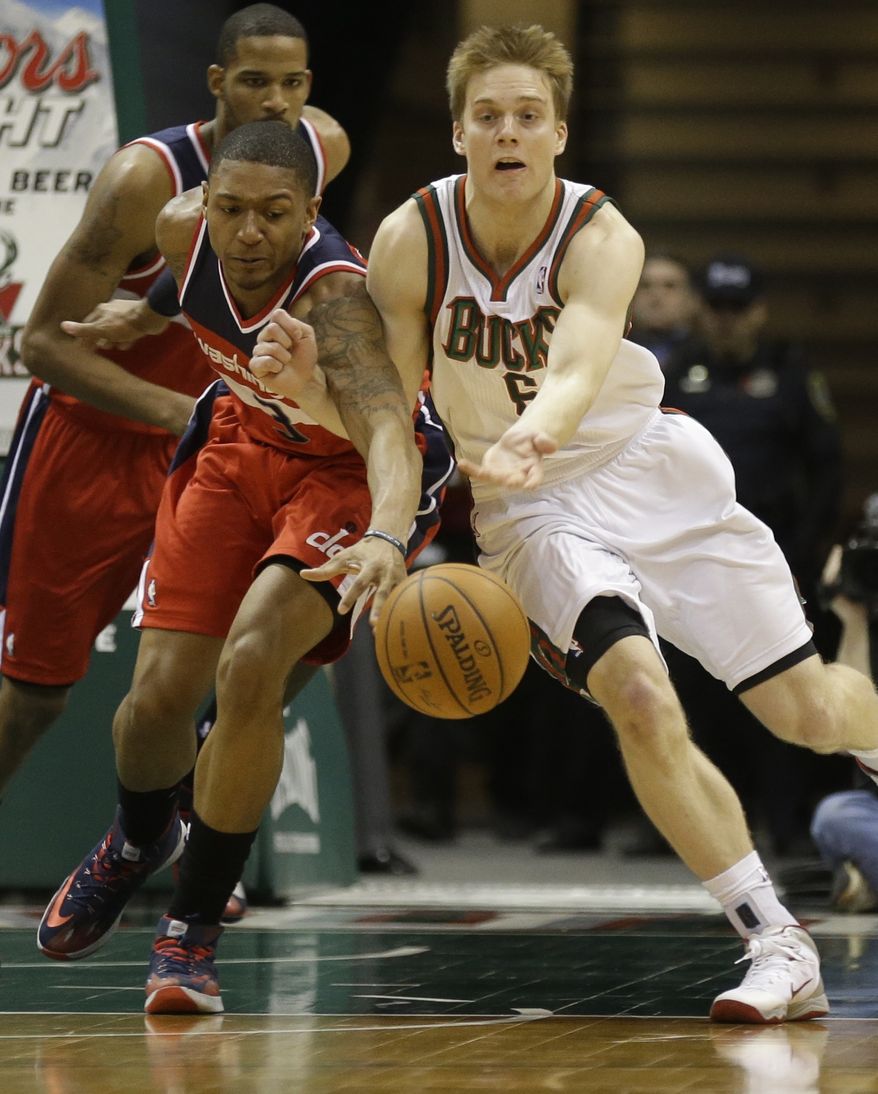 Washington Wizards' Bradley Beal, left, and Milwaukee Bucks' Nate Wolters reach for a loose ball during the first half of an NBA basketball game on Saturday, March 8, 2014, in Milwaukee. (AP Photo/Jeffrey Phelps)