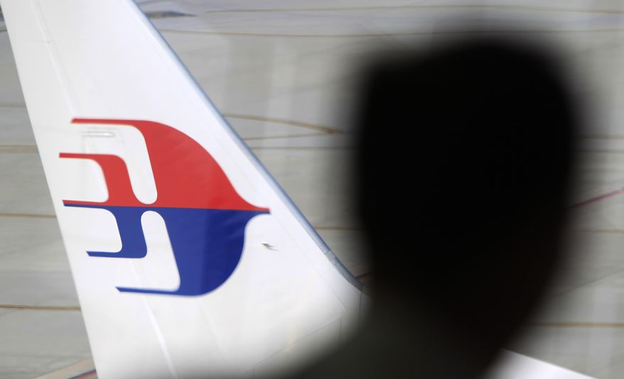 A man looks out from a viewing gallery as a Malaysia Airlines aircraft sits on the tarmac at Kuala Lumpur International Airport in Sepang, Malaysia, Sunday, March 9, 2014. Vietnamese ships and planes hunting for a missing Malaysian jetliner have found no wreckage close to where they spotted two large oil slicks. The Boeing 777 carrying 239 people disappeared off radar screens early Saturday less than an hour after taking off from Kuala Lumpur bound for Beijing. (AP Photo/Lai Seng Sin)