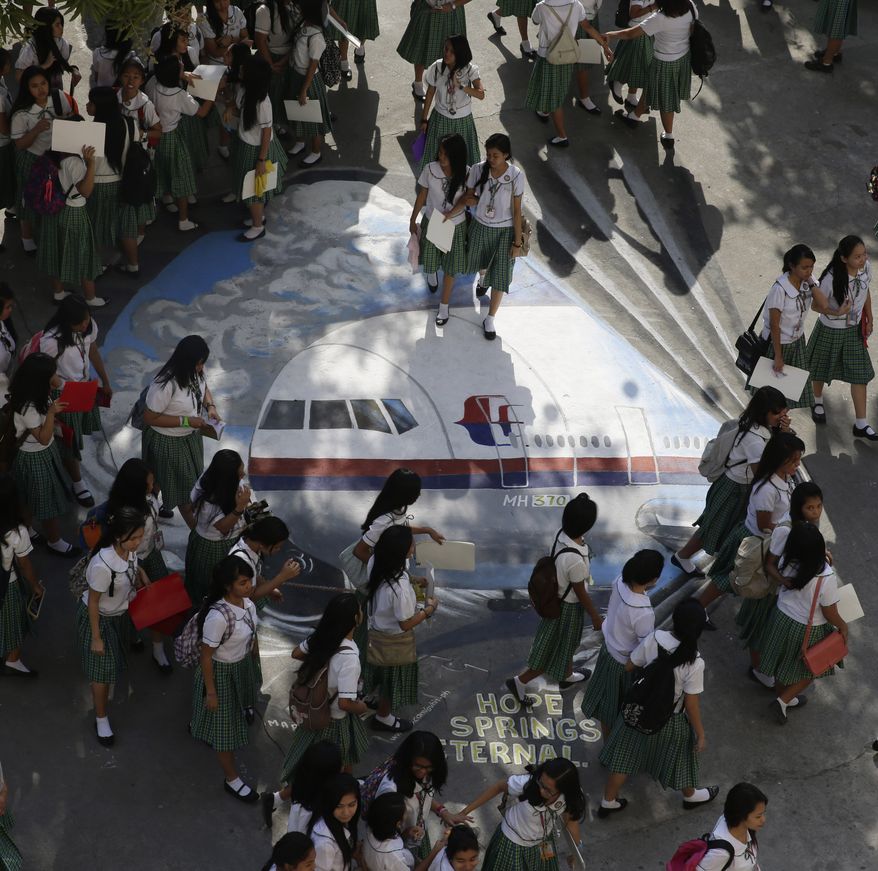 Students from the Benigno "Ninoy" Aquino High School walk on a mural depicting the missing Malaysia Airlines plane Tuesday, March 18, 2014 at their campus at Makati city, east of Manila, Philippines. Officials revealed a new timeline Monday suggesting the final voice transmission from the cockpit of the missing Malaysian plane may have occurred before any of its communications systems were disabled, adding more uncertainty about who aboard might have been to blame. The search for Flight 370, which vanished early March 8 while flying from Kuala Lumpur to Beijing with 239 people on board, has now been expanded deep into the northern and southern hemispheres. (AP Photo/Bullit Marquez)