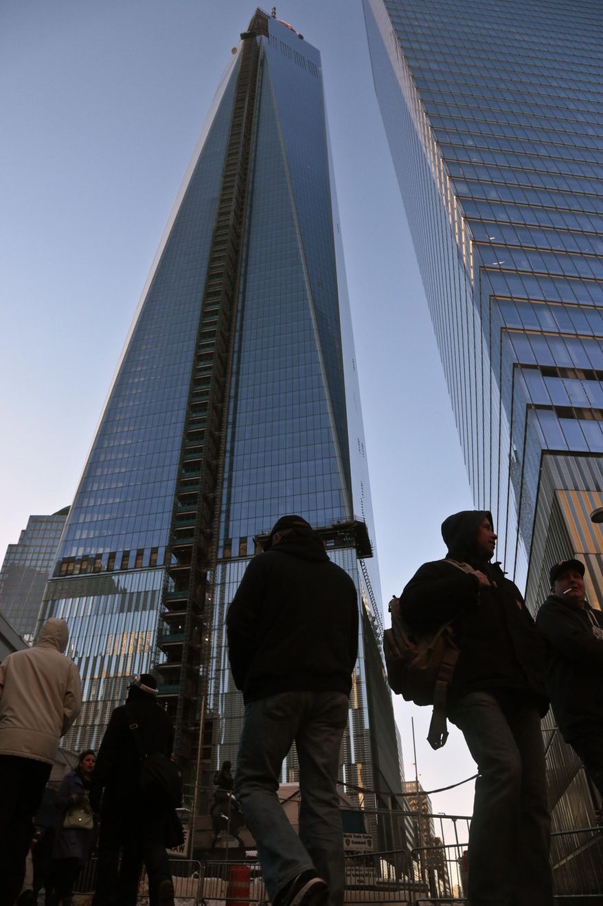 FILE. - This Feb. 11, 2014 file photo shows pedestrians in front of the 1 World Trade Center building, left, in New York. A 16-year-old boy from Weehawken, N.J., is accused of bypassing security in the middle of the night and climbing a ladder to the spire of 1 World Trade Center to take pictures according the the Port Authority of New York and New Jersey. The teen was arrested on the premises at 6 a.m. Sunday March 16, 2014 and his camera and cellphone were seized after authorities obtained a search warrant. He was later released without bail. (AP Photo/Bebeto Matthews, File)