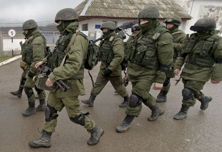 Pro-Russian soldiers march outside an Ukrainian military base in Perevalne, Crimea, Thursday, March 20, 2014. With thousands of Ukrainian soldiers and sailors trapped on military bases, surrounded by heavily armed Russian forces and pro-Russia militia, the Kiev government said it was drawing up plans to evacuate its outnumbered troops from Crimea back to the mainland and would seek U.N. support to turn the peninsula into a demilitarized zone.(AP Photo/Vadim Ghirda)