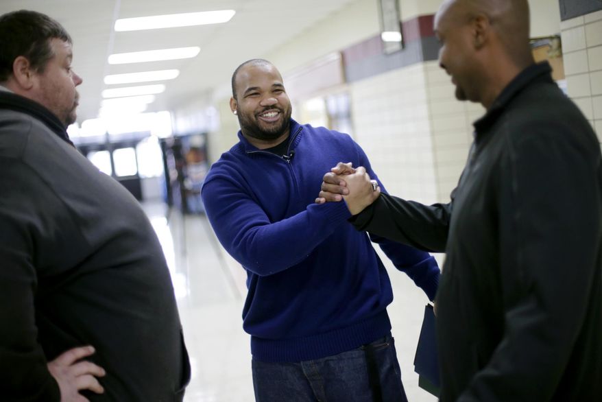 In this photo taken on Tuesday, March 25, 2014, University of Tulsa student Shawn Jackson, center, greets coaches Danny Clark, right, and Michael Davis Sr., following a ceremony that honored his achievements at his alma mater, McLain High School for Science and Technology in Tulsa, Okla. Jackson, who was named Conference USA's defensive player of the year while playing at Tulsa, played football when he was a student at McLain and was honored during an assembly for students. (AP Photo/Tulsa World, John Clanton) ONLINE OUT; KOTV OUT; KJRH OUT; KTUL OUT; KOKI OUT; KQCW OUT; KDOR OUT; TULSA OUT; TULSA ONLINE OUT