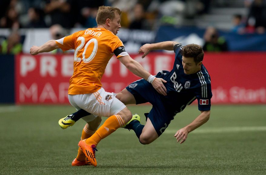 Houston Dynamo's Andrew Driver, left, of England, and Vancouver Whitecaps' Jordan Harvey collide during the first half of an MLS soccer game in Vancouver, British Columbia, Saturday, March 29, 2014. (AP Photo/The Canadian Press, Darryl Dyck)