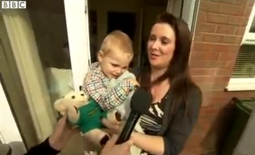 Dana Henry with 2-year-old Riley Ward, who called emergency services when his mother collapsed. (BBC News via YouTube)