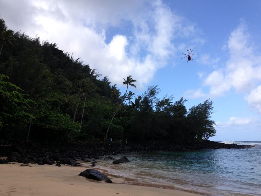 A Kauai County Fire Department helicopter flies along Kauai's Napali Coast to rescue hikers stranded by rising waters crossing a trail in Kapaa, Hawaii, on Monday, April 7, 2014. (AP Photo/Rachel La Corte)