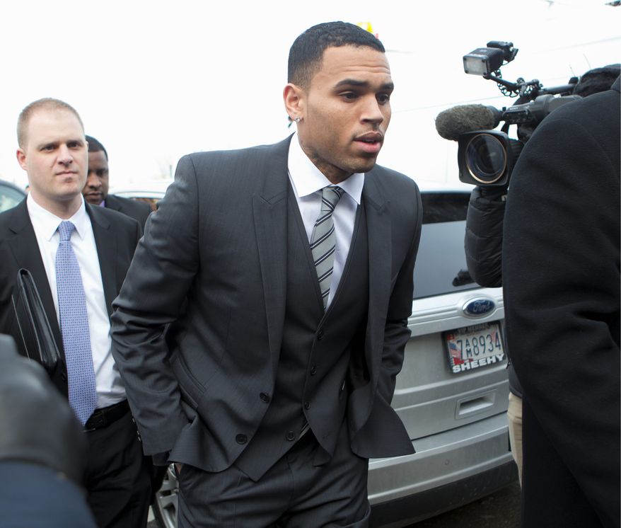 FILE - In this Wednesday, Jan. 8, 2014 file photo, singer Chris Brown, right, arrives at the District of Columbia Superior Court in Washington, for a status hearing in a case in which he's accused of hitting a man outside a Washington hotel. Lawyers for Brown are due back in a Washington court Thursday Feb. 20, 2014 to determine a date for his trial on a misdemeanor assault charge, but the singer won't be in town. (AP Photo/Manuel Balce Ceneta, File)