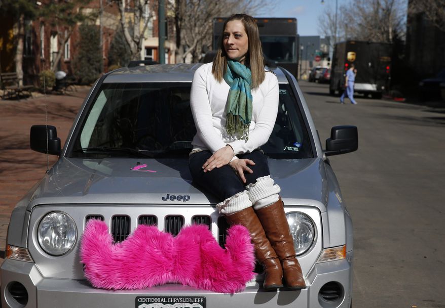 FILE - In this Feb. 28, 2014 file photo, part time Lyft driver Brittany Cameron sits on the hood of her own vehicle, which she uses to give rides, and which is adorned with Lyft's trademark pink mustache, in downtown Denver. Lyft is a transportation network company whose mobile-phone application facilitates peer-to-peer ride sharing by enabling passengers who need a ride to request one from drivers who have a car. Internet companies like Lyft that connect riders to drivers with a few taps on a cellphone app will be regulated in Colorado with legislation soon to become law, putting the state at the forefront of a push to try to legitimize the flourishing tech startups. (AP Photo/Brennan Linsley)