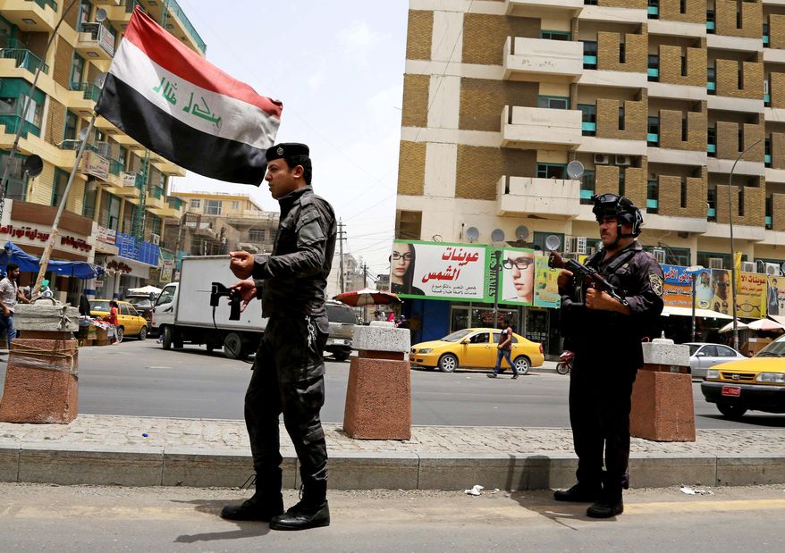 Iraqi federal policemen stand guard at a checkpoint in Baghdad, Iraq, Wednesday, June. 11, 2014. (AP Photo/ Karim Kadim)
