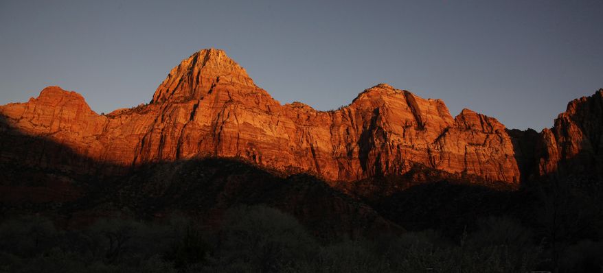 FILE - This Jan. 20, 2011 file photo shows shadows creeping up on sandstone cliffs glowing red as the sun sets on Zion National Park near Springdale, Utah. The National Park Service is taking steps to ban drones from 84 million acres of public lands and waterways, saying the unmanned aircraft annoy visitors, harass wildlife and threaten safety. Jonathan Jarvis, the park service’s director, told The Associated Press he was signing a policy memorandum on Friday directing superintendents of the service’s 401 parks to write rules prohibiting the launching, landing or operation of unmanned aircraft in their parks. (AP Photo/Julie Jacobson, file)