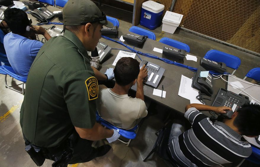 FILE - This June 18, 2014, file photo shows a U.S. Customs and Border Protection officer as he helps a few boys to make phone calls, some of the hundreds of mostly Central American immigrant children that are being processed and held at the U.S. Customs and Border Protection Nogales Placement Center in Nogales, Ariz. Thousands of immigrant children crossing alone into the U.S. can live in American cities, attend public schools and possibly work here for years without consequences. The chief reasons are an overburdened, deeply flawed system of immigration courts and a 2002 law intended to protect children's welfare, an Associated Press investigation finds. (AP Photo/Ross D. Franklin, Pool, File)