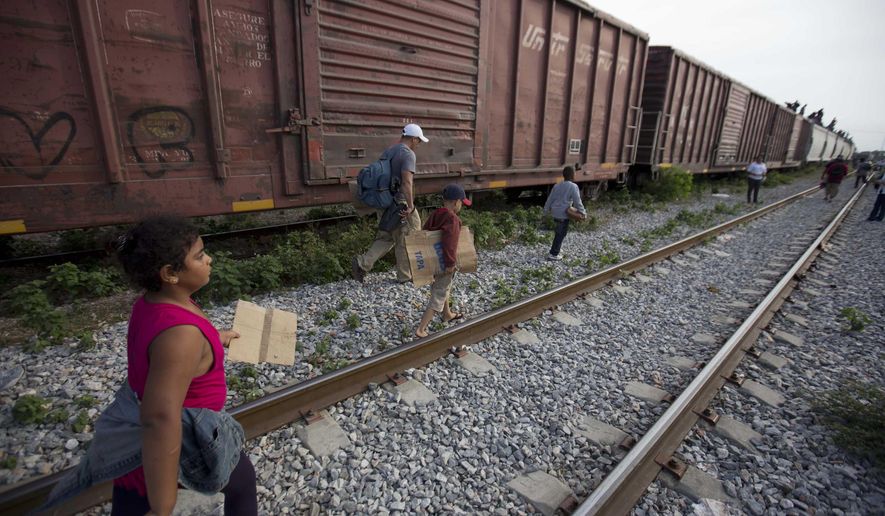 In this July 12, 2014, photo, migrants walk along the rail tracks after getting off a train during their journey toward the U.S.-Mexico border in Ixtepec, Mexico. The surge in unaccompanied minors and women with children migrating from Central America has put new attention on decades-old smuggling organizations.  (AP Photo/Eduardo Verdugo)