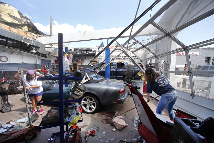 Master Auto manager Marie Annaloro, left, and Victoria Ohlson,right, sweep glass and debris in the service garage where the roof blew off in Revere, Mass. Monday, July 28, 2014, after a tornado touched down. Revere Deputy Fire Chief Mike Viviano says the fire department in that coastal city has received dozens of calls reporting partial building and roof collapses, and downed trees and power lines. Viviano says there are no immediate reports of deaths or serious injuries. (AP Photo/Elise Amendola)