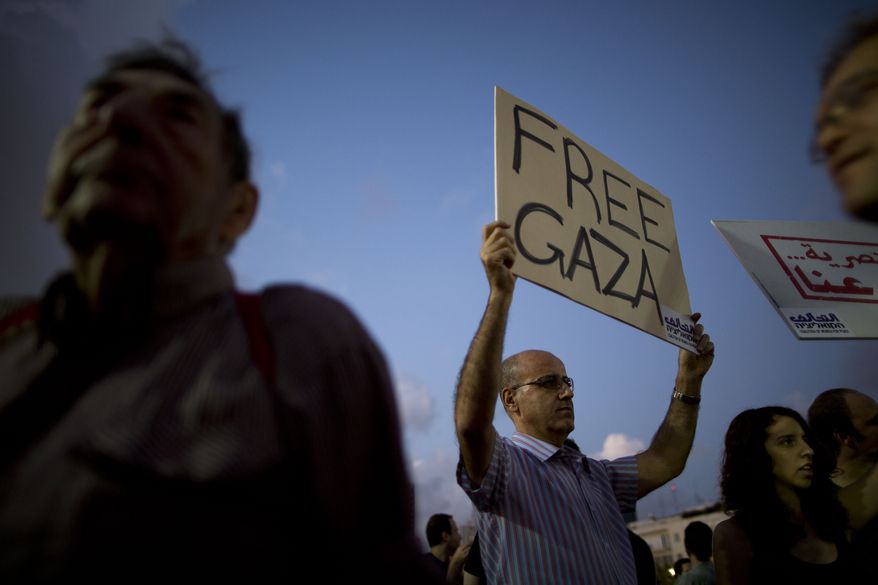 FILE - In this file photo taken Saturday, July 19, 2014, an Israeli left-wing activist holds a sign during a demonstration against Israel's operation in the Gaza Strip, in Tel Aviv, Israel. Despite Israeli casualties and world criticism, a near-consensus in Israel supports the government’s conduct of the Gaza war, views Hamas as the aggressor and considers outsiders' moralizing as hypocritical, ignorant or both. A small but vocal opposition exists, but those arguing for peace are vociferously shouted down in a way rarely seen in a country long proud of its spirited, democratic debate. (AP Photo/Oded Balilty, File)