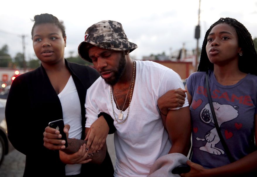 A man is helped by two women following an encounter with police Monday, Aug. 11, 2014, in Ferguson, Mo. The FBI opened an investigation Monday into the death of 18-year-old Michael Brown, who police said was shot multiple times Saturday after being confronted by an officer in Ferguson. Authorities in Ferguson used tear gas and rubber bullets to try to disperse a large crowd Monday night that had gathered at the site of a burned-out convenience store damaged a night earlier, when many businesses in the area were looted. (AP Photo/Jeff Roberson)