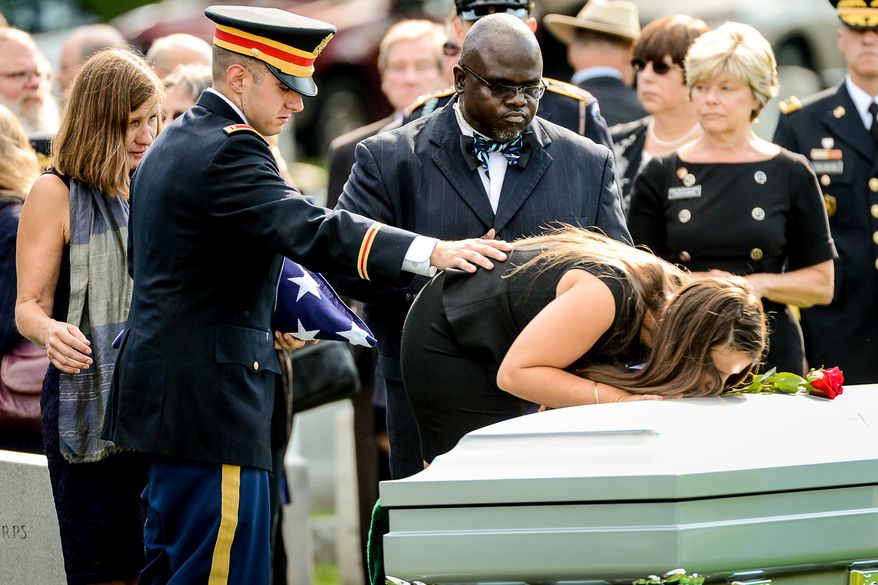 The family of Army Maj. Gen. Harold J. Greene, from left, wife Dr. Susan Myers, son Army 1st Lt. Matthew Greene, and daughter Amelia Greene, each take turns placing a rose on his coffin during his funeral service at Section 60 at Arlington National Cemetery, Arlington, Va., Thursday, August 14, 2014. Greene was killed in Afghanistan while at the national military academy in Kabul. He was the highest-ranking U.S. Army officer killed in combat since the Vietnam War. (Andrew Harnik/The Washington Times)