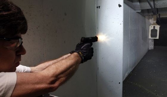 Dimitry Lazar fires his 9mm pistol at targets at the Firing-Line indoor range and gun shop, Thursday, July 26, 2012 in Aurora, Colo. The massacre inside a crowded Colorado movie theater has prompted a sudden increase in gun sales and firearms training. (AP Photo/Alex Brandon)