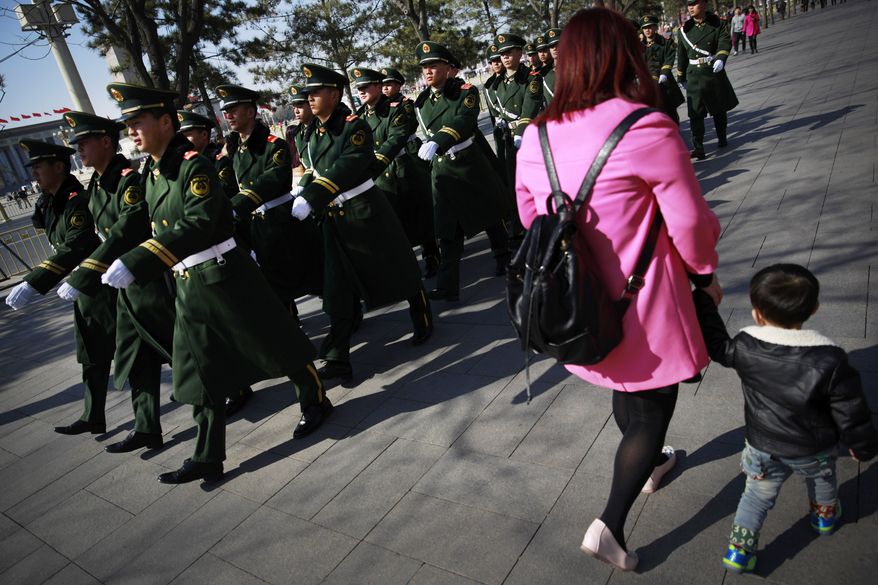 Chinese paramilitary policemen march past a woman and a child near Tiananmen Square in Beijing Wednesday, March 4, 2015. China&#39;s military budget will grow by about 10 percent in the coming year, a legislative spokeswoman said Wednesday, despite slowing economic growth that fell to 7.4 percent last year and is expected to further decline in 2015. (AP Photo/Andy Wong)