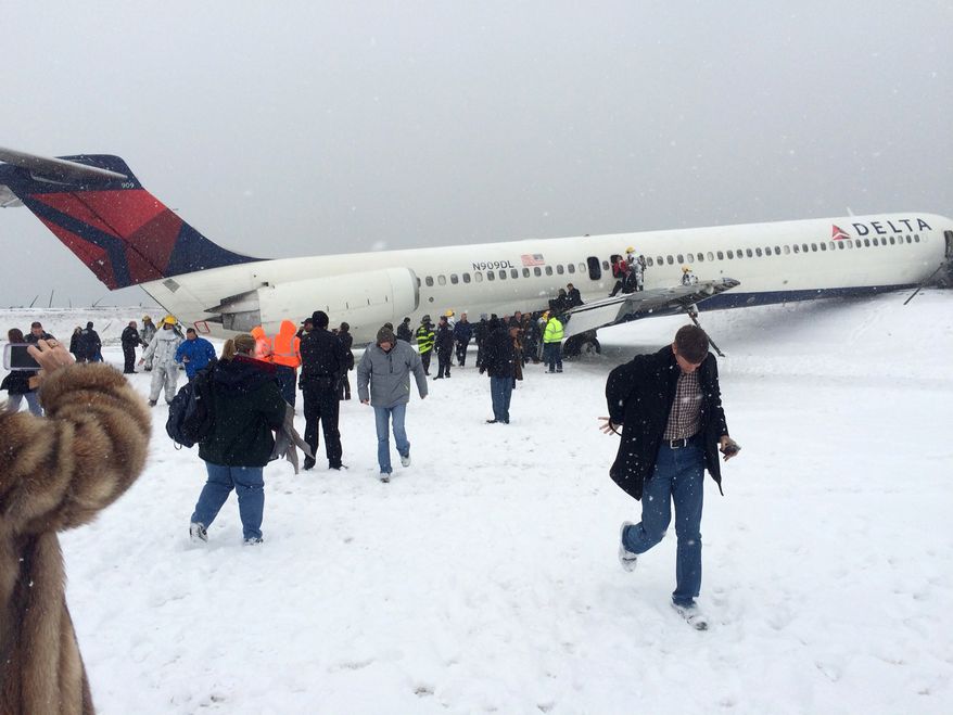 In this photo provided by passenger Amber Reid, passengers are evacuated after a Delta plane skidded off the runway while landing at LaGuardia Airport during a snowstorm, Thursday, March 5, 2015, in New York. Authorities said the plane, from Atlanta, carrying 125 passengers and five crew members, veered off the runway at around 11:10 a.m. before crashing through a chain-link fence and coming to rest with its nose perilously close to the edge of an icy bay. (AP Photo/Amber Reid)